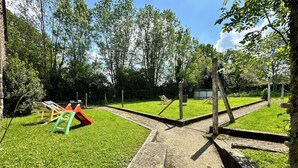 Un parque infantil con columpios, toboganes y una pequeña estructura para escalar.