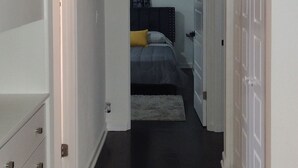A hallway leading to a bedroom with a bed, a dresser, and a ceiling light. - Deco style spacious remodeled house in the heart of Sebring close to everything. (Sebring)