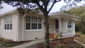 A single-story house with a front porch, a small staircase, and a well-maintained lawn. - Deco style spacious remodeled house in the heart of Sebring close to everything. (Sebring)