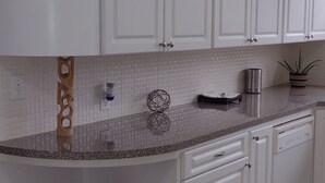 A kitchen with white cabinets, a granite countertop, and a built-in dishwasher. - Deco style spacious remodeled house in the heart of Sebring close to everything. (Sebring)