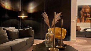 A modern living room with a sofa, a round table with candles, and a lamp. - Water Villa in Heeg by Heegermeer (Heeg)