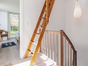 A wooden staircase with a handrail, a light fixture, and a view of an outdoor area with a chair and a bed. - 6 Person Holiday Home in Thyholm (Thyholm)