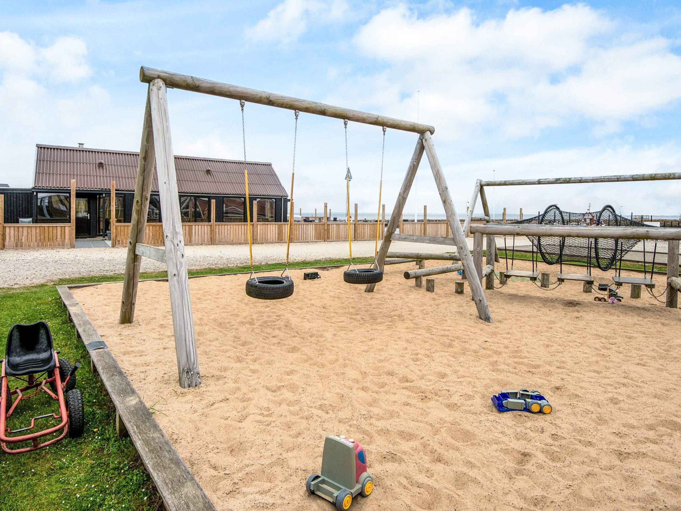 Une aire de jeux avec des balançoires, des balançoires en forme de pneu et une voiture faite de pneus.