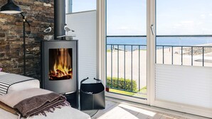 A balcony with a wood-burning stove, a view of the sea, and a stone wall. - 6 Person Holiday Home in Thyholm (Thyholm)