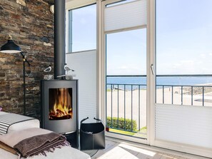 A balcony with a wood-burning stove, a view of the sea, and a stone wall.