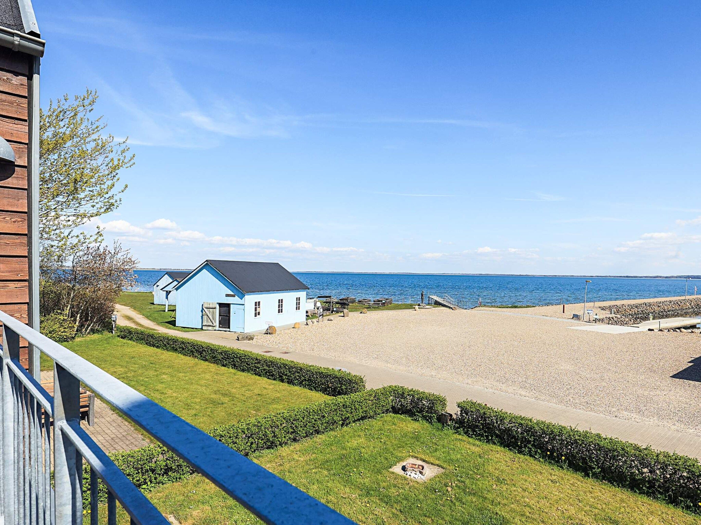 Una propietat costanera amb una casa blava, una platja de grava i una vista clara del mar.