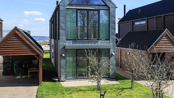 A modern two-story house with a large glass window, a sloped roof, and a small porch. - 6 Person Holiday Home in Thyholm (Thyholm)
