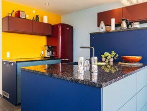 A kitchen with a central island, a red refrigerator, and a coffee machine.