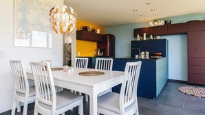 A modern kitchen with a dining area, featuring a white dining table with chairs, a unique spherical light fixture, and a map on the wall. - 6 Person Holiday Home in Thyholm (Thyholm)