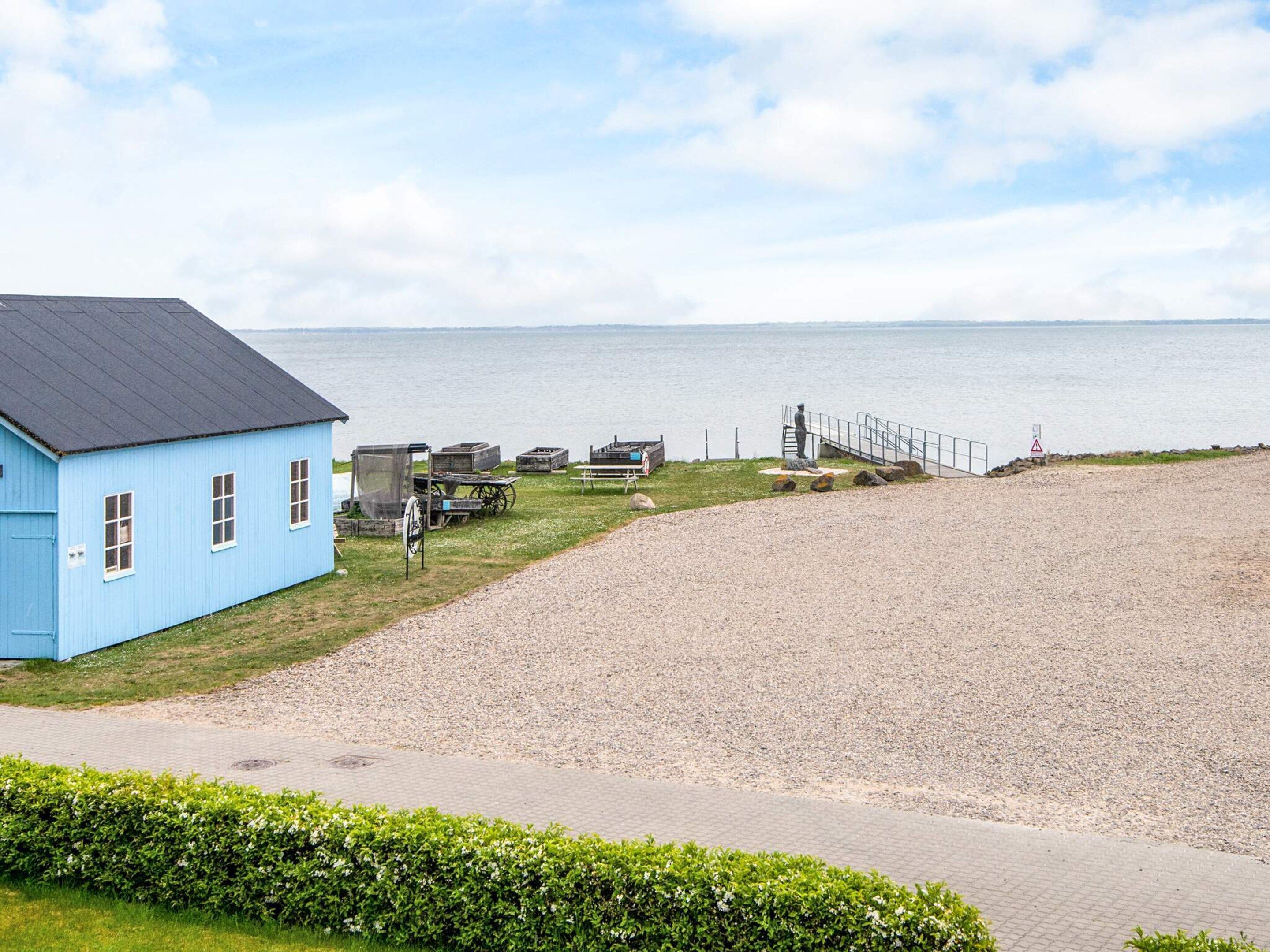 A blue building with a gravel path leading to a beach.