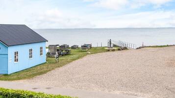 A blue building with a gravel path leading to a beach.