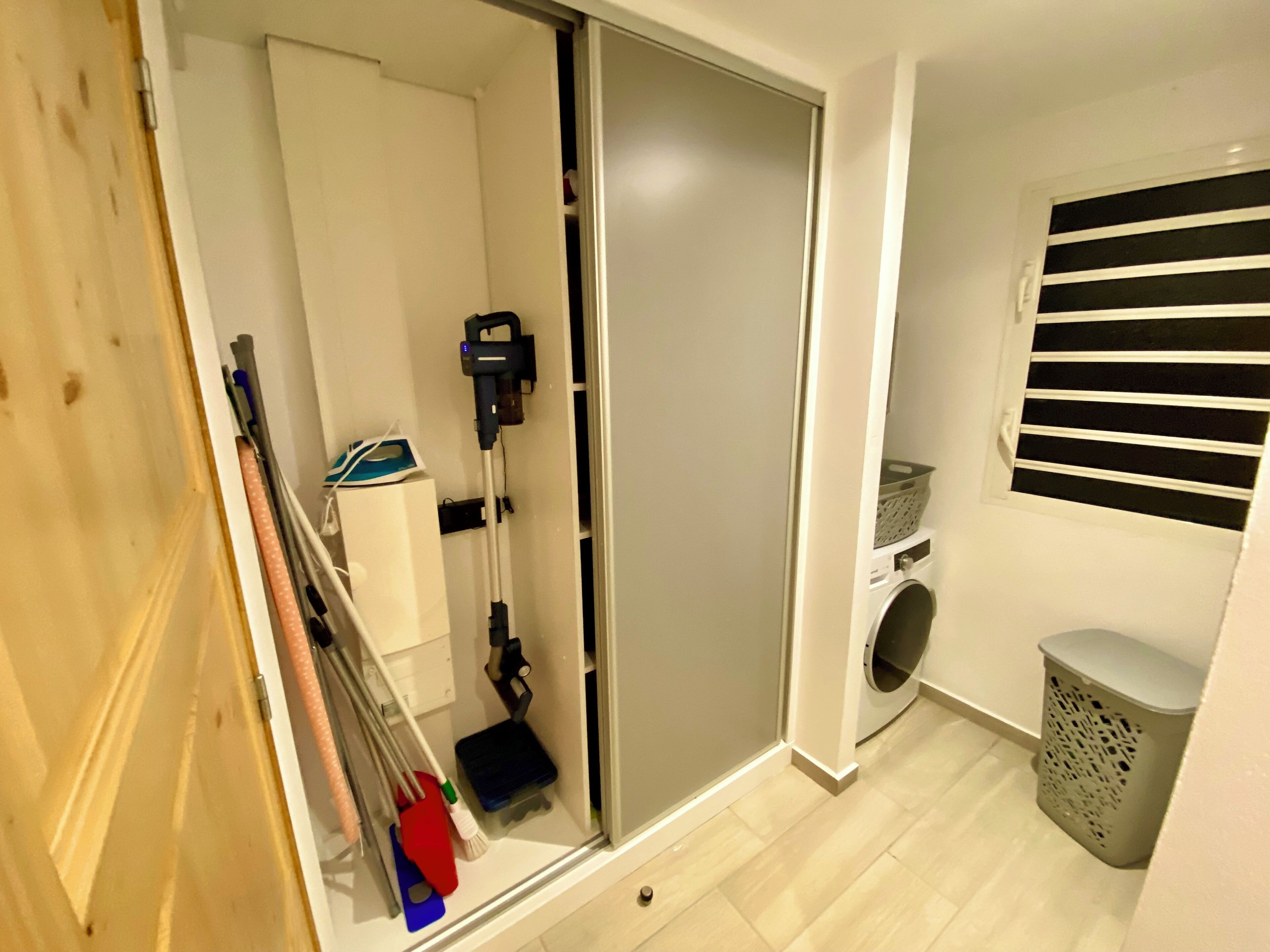 A laundry room with a washing machine, a drying rack, and a laundry basket.