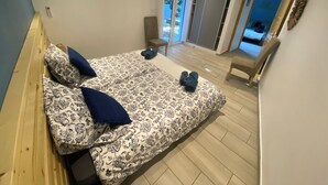 A bedroom with a bed, a chair, and a view of the outside. - Ti Case Fleur Letchi - Cadre Calme et Agréable, Avec Jardin (Les Avirons)