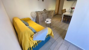 A bedroom with a bed, a desk, and a chair. There is a wardrobe and a television on the wall. - Ti Case Fleur Letchi - Cadre Calme et Agréable, Avec Jardin (Les Avirons)
