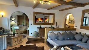 A rustic interior with a wooden ceiling, a fireplace, a sofa, and a cowhide rug.