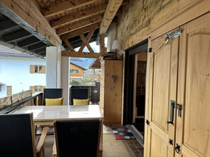 A wooden interior with a dining table and chairs, a wooden door, and a view of the outside. - Pure Mountain Partenkirchen (Garmisch-Partenkirchen)