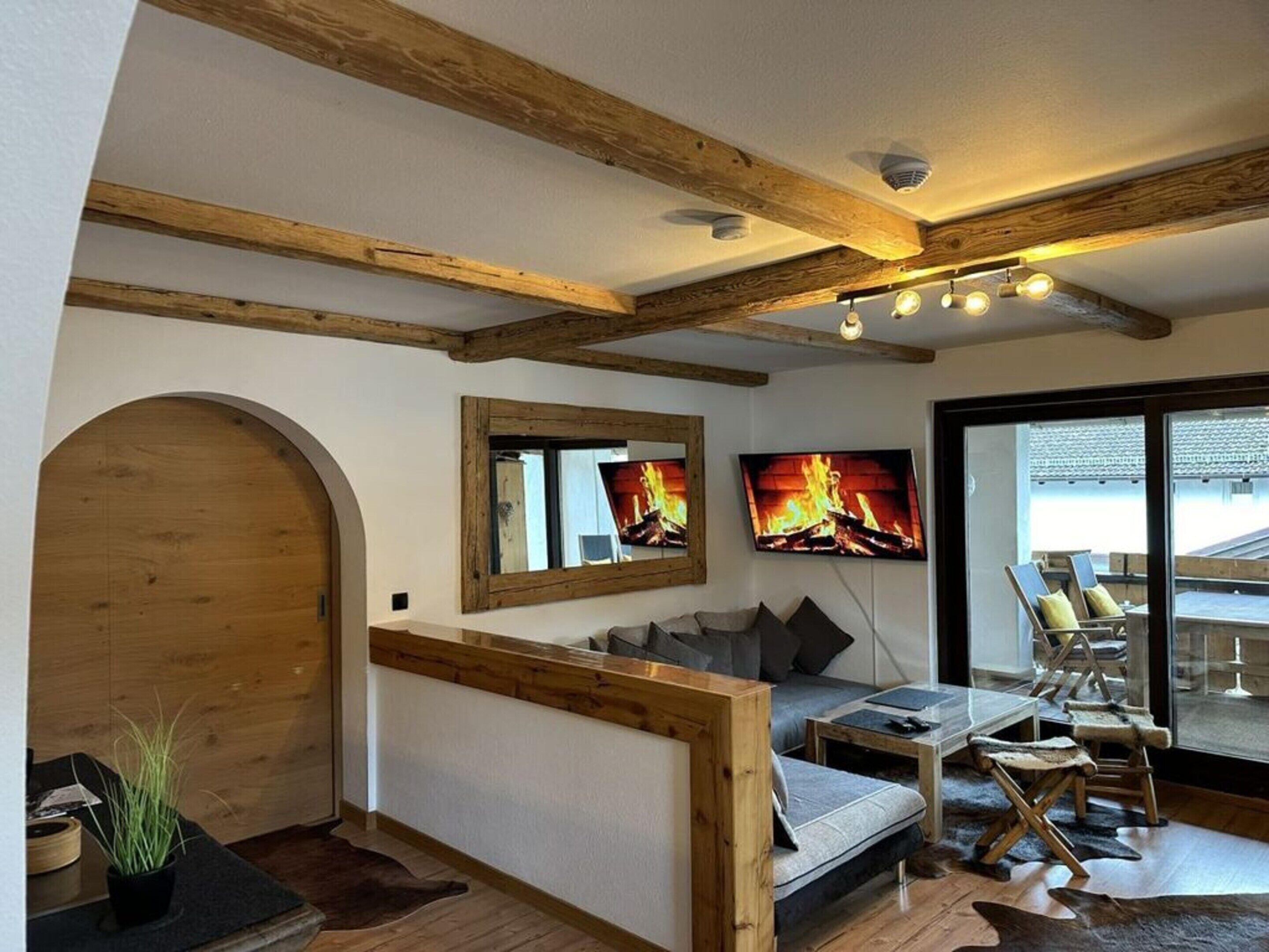 A cozy living room with a fireplace, a sofa, a TV, and a view of the outdoors.