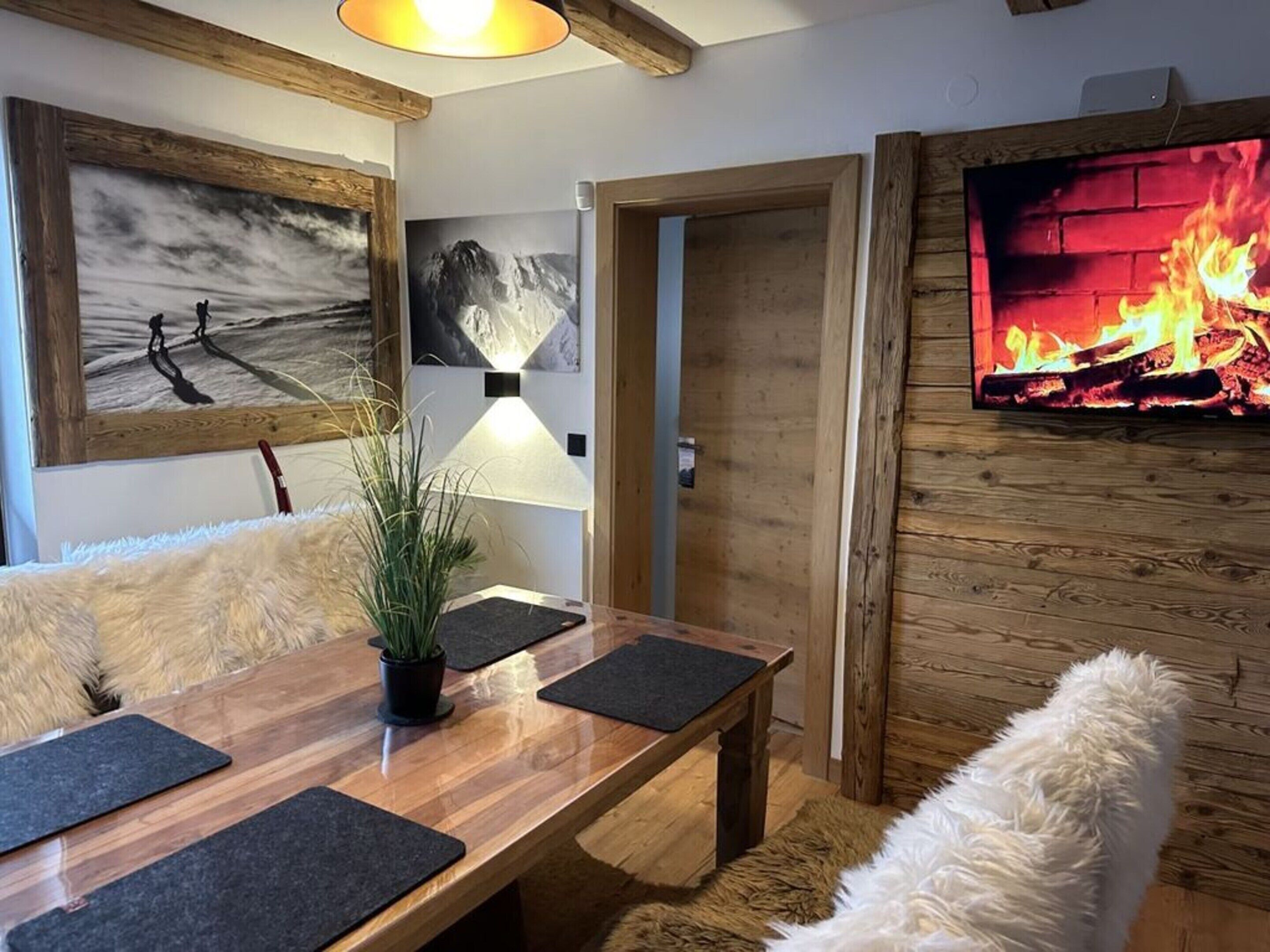 Ein gemütliches Wohnzimmer mit Holzesstisch, einer Couch und einem Kamin.