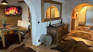 A room with a wooden dining table, a sofa, a mirror, a cabinet, and a cowhide rug.