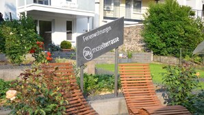 Un'area giardino con un cartello che indica 'Ferienwohnungen m. moselterrasse'.
