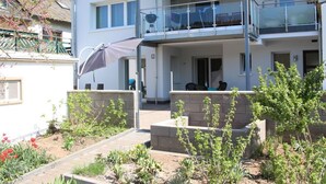 Un edificio residenziale a due piani con un balcone, posti a sedere all'aperto e un'area giardino.