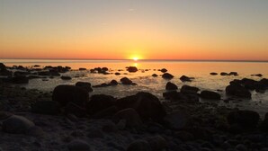 A beach with rocks and the sun setting over the water. - Red-throated Diver Modern Retreat (Putgarten)