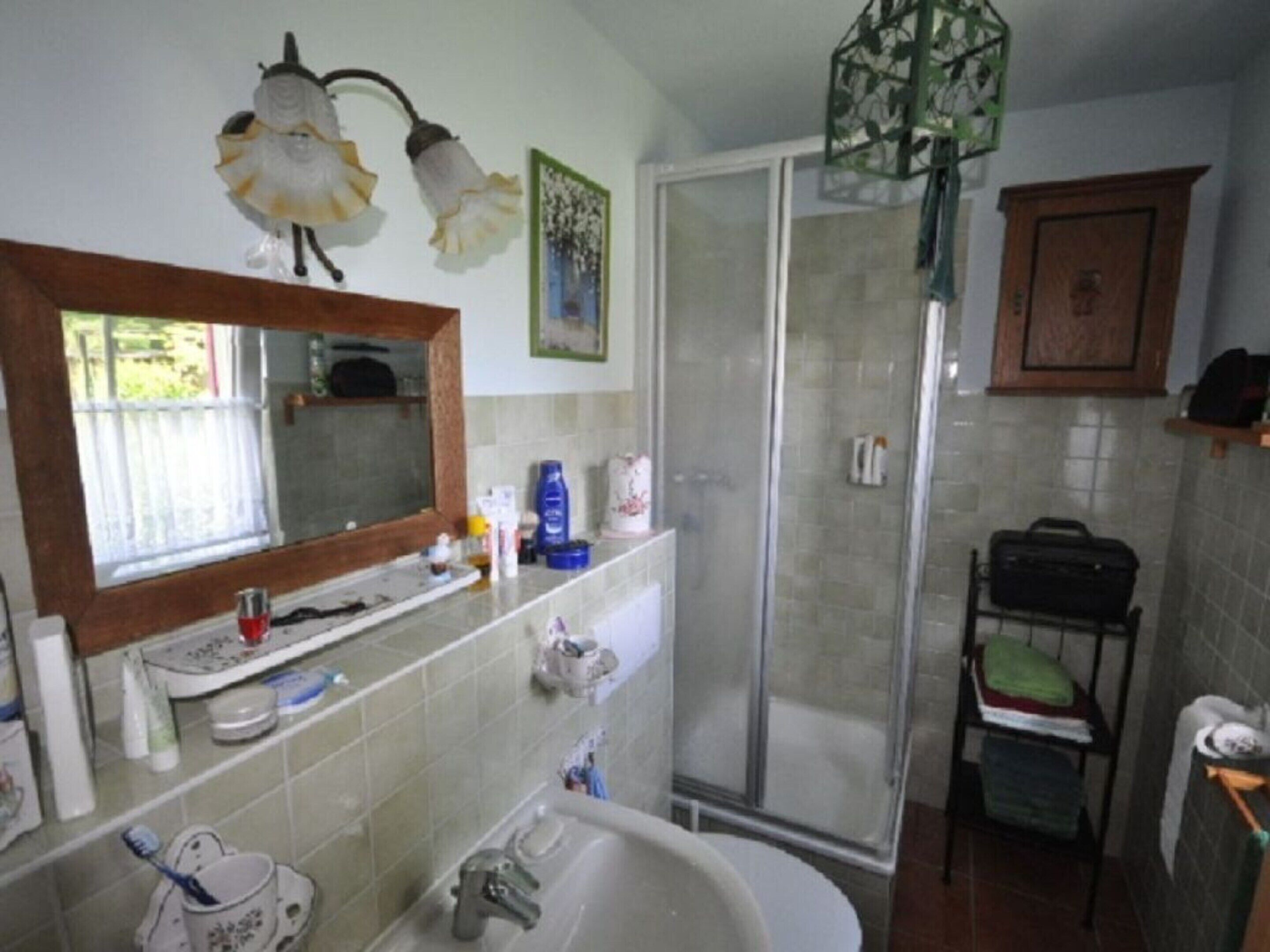 Une salle de bain équipée d’une douche, d’un lavabo, d’un miroir et d’un meuble de rangement.