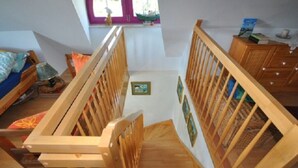 A staircase with wooden railings leading to a bedroom with a bed and a dresser. - Red-throated Diver Modern Retreat (Putgarten)