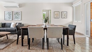 A dining area with a table and chairs, a sofa, and a large window with a view. - #3 - Charming Spanish Colonial Apartment - Miramar (San Juan,)