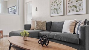 A modern living room with a grey sofa, a wooden coffee table, and a potted plant. - #3 - Charming Spanish Colonial Apartment - Miramar (San Juan,)