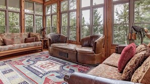 Una habitación acogedora con ventanas amplias, un tapete estampado y muebles de cuero.