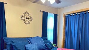 Ein Schlafzimmer mit einem großen Bett, einem Deckenventilator und blauen Vorhängen.