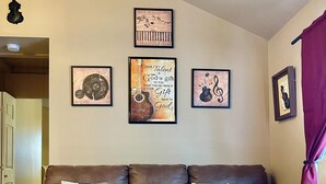 Ein Wohnzimmer mit einem braunen Ledersofa, einem Couchtisch mit Büchern und gerahmten Wandbildern.
