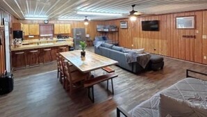 Un'ampia zona giorno con soffitto in legno, un tavolo da pranzo con sedie, un divano e un letto.