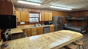 Cucina spaziosa con mobili in legno, una grande isola con sgabelli, un frigorifero e un lavandino.
