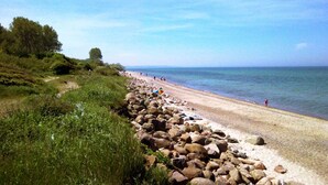 A beach with a rocky shoreline, a clear sky, and a few people in the distance. - Holiday Apartment in Thuringia (Zierow)