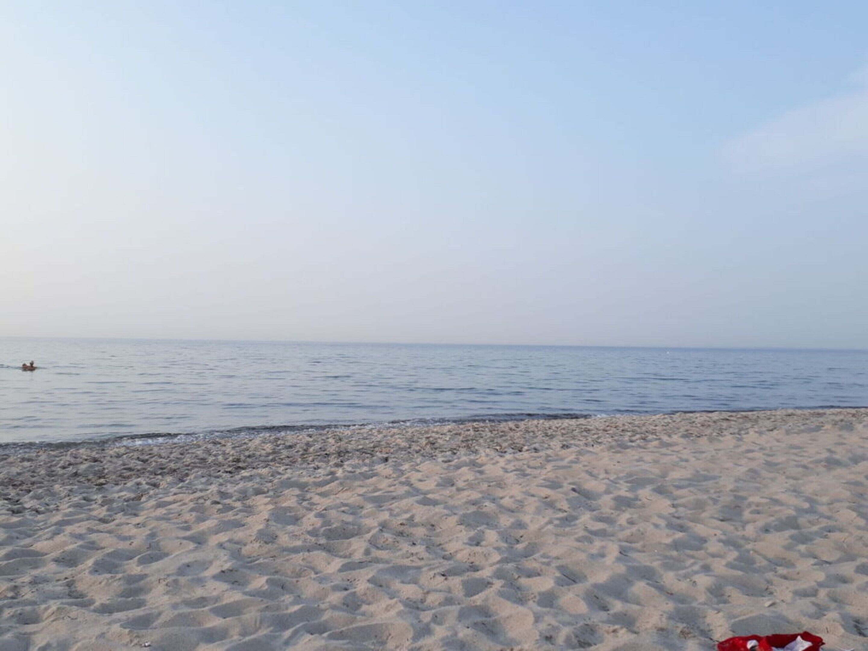 A sandy beach with a calm sea and a clear sky.