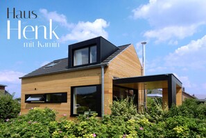 A modern house with a wooden facade and large windows, surrounded by lush greenery. - Holiday Apartment in Thuringia (Zierow)