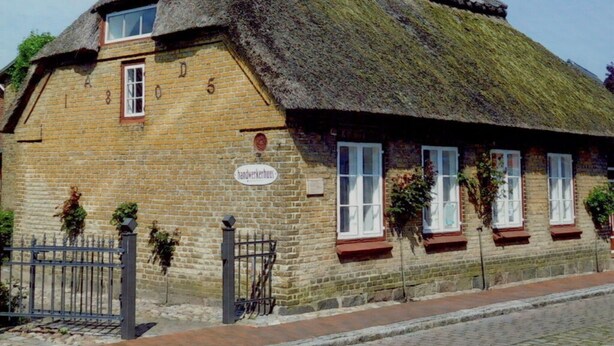 A traditional thatched-roof house with a brick facade, numbered windows, and a sign indicating it is a handwork house. - Seebergweg Modern Retreat (Maasholm)