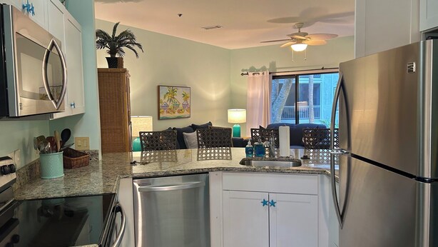 Una cocina moderna con electrodomésticos de acero inoxidable, lavavajillas y un comedor con vistas.