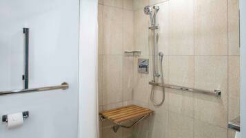 Un baño moderno con ducha, barras de apoyo y un perchero para toallas.