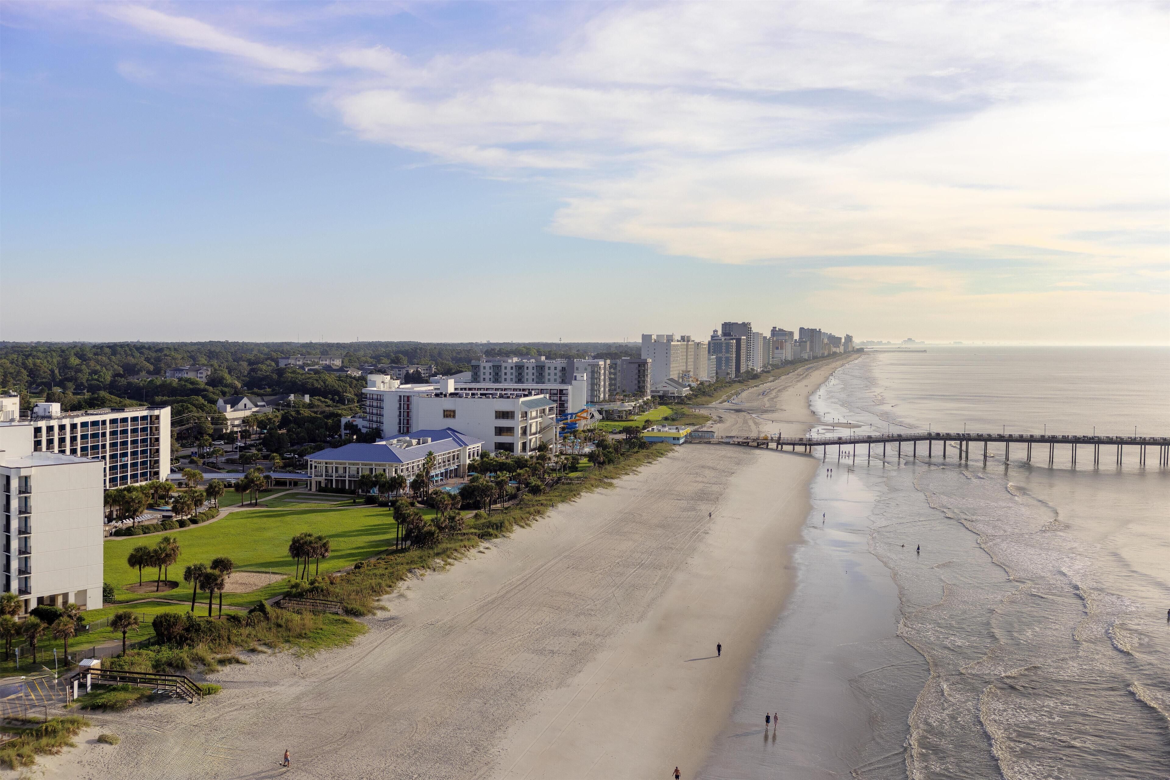 A beachside hotel with a long promenade, beachfront access, and a view of the ocean.