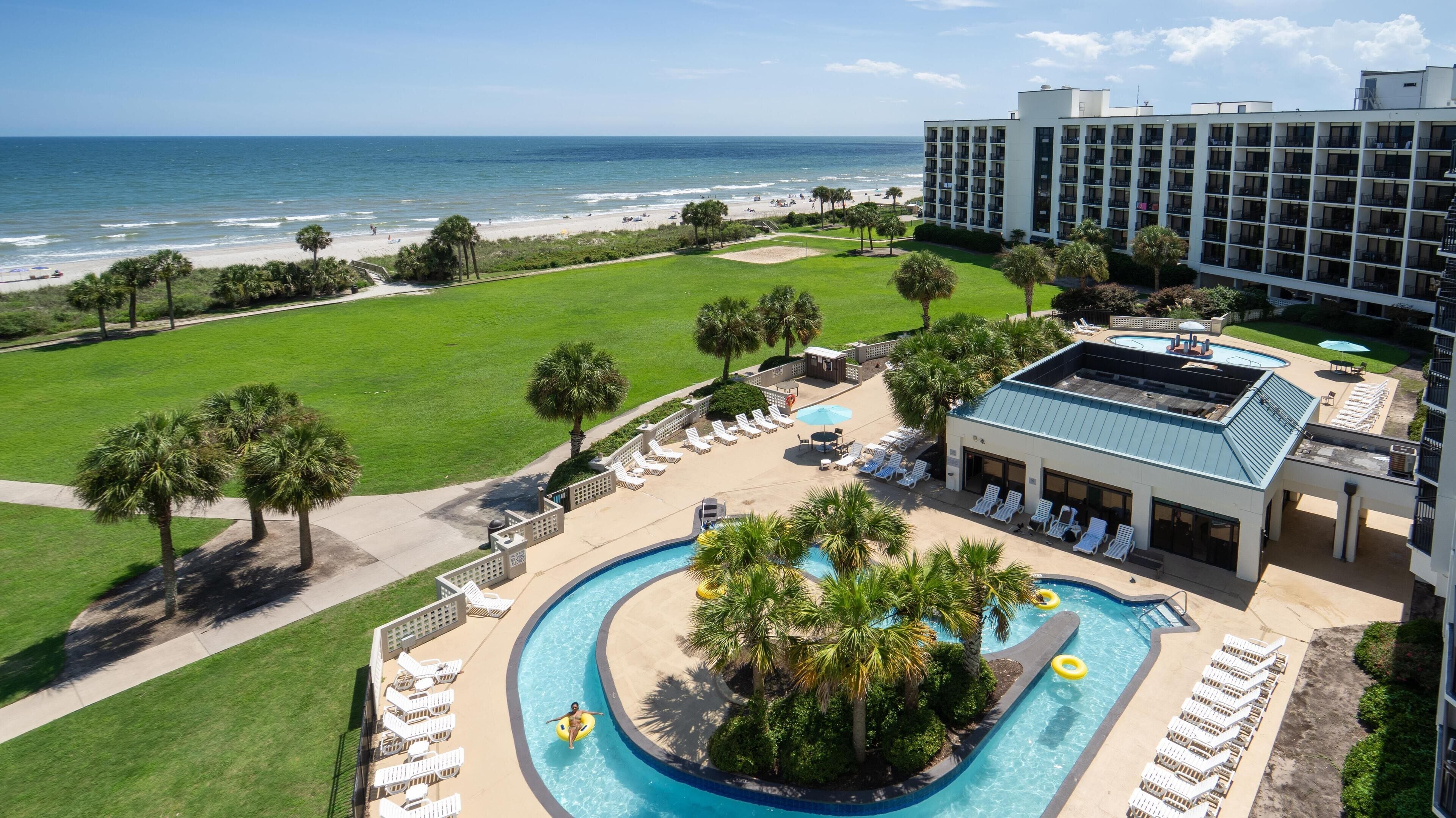 A hotel with a pool, beach view, and multiple floors.