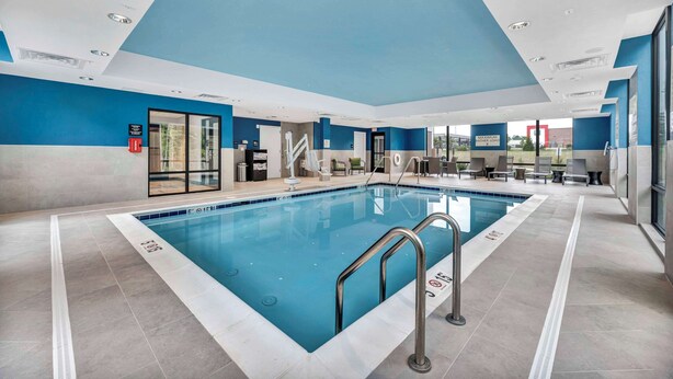 A swimming pool with a blue and white color scheme, surrounded by a lounge area with seating and a staircase.