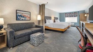 A hotel room with a sofa, a bed, a desk, and a chair. - Home2 Suites By Hilton Reynoldsburg Columbus East (Reynoldsburg)