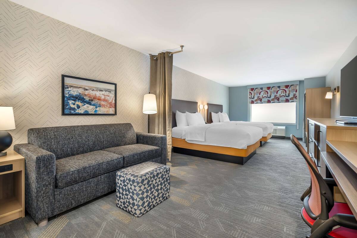 A hotel room with a sofa, a bed, a desk, and a chair.