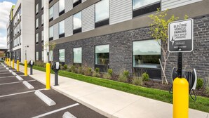 A modern building with a sign indicating electric vehicle parking and charging, guest use only, and a Hilton logo. - Home2 Suites By Hilton Reynoldsburg Columbus East (Reynoldsburg)