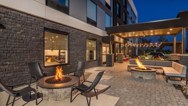 An outdoor patio with a fire pit, seating, and a covered area with string lights. - Home2 Suites By Hilton Reynoldsburg Columbus East (Reynoldsburg)