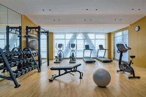 Un gimnasio moderno con equipo de ejercicio, cintas de correr y un espejo grande.