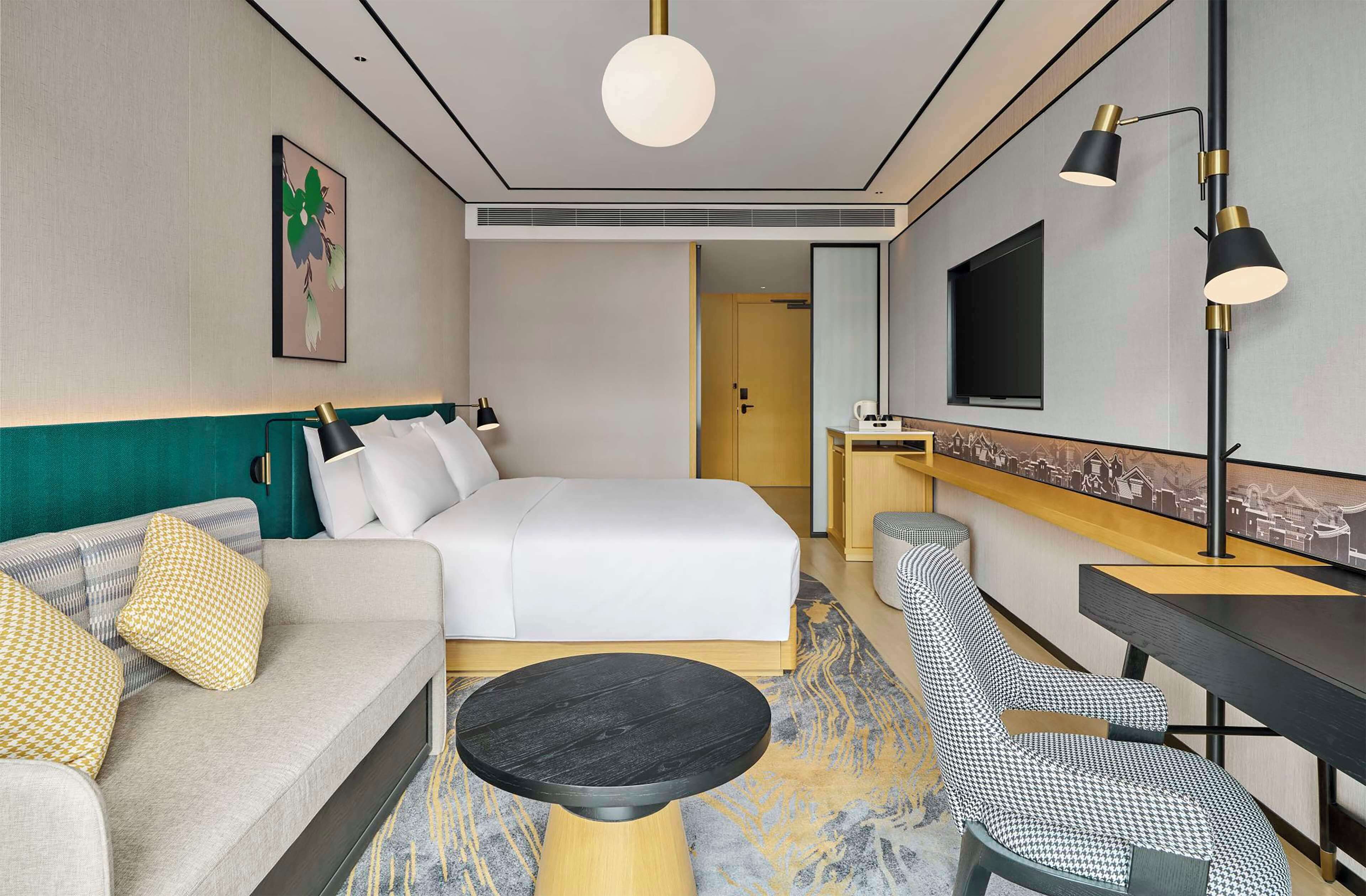 Una habitación de hotel con cama, sofá, escritorio, silla y televisor.